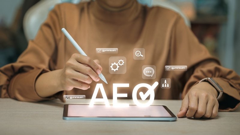 Businesswoman using digital tablet with AEO hologram. Concept of Authorized Economic Operator, customs compliance, supply chain security, and global trade standard certification.