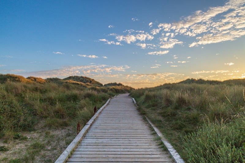 A wooden pathway leading towards the sea at Formby in Merseyside, taken at sunset