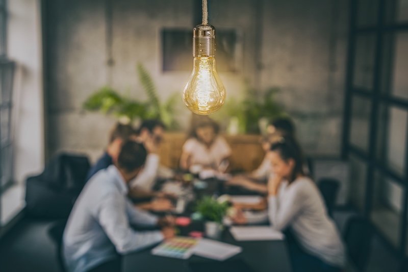 Young business people are discussing together a new startup project. A glowing light bulb as a new idea.