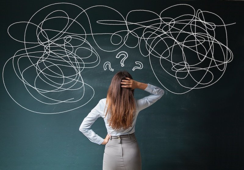 Confused business woman staring at scribble on blackboard