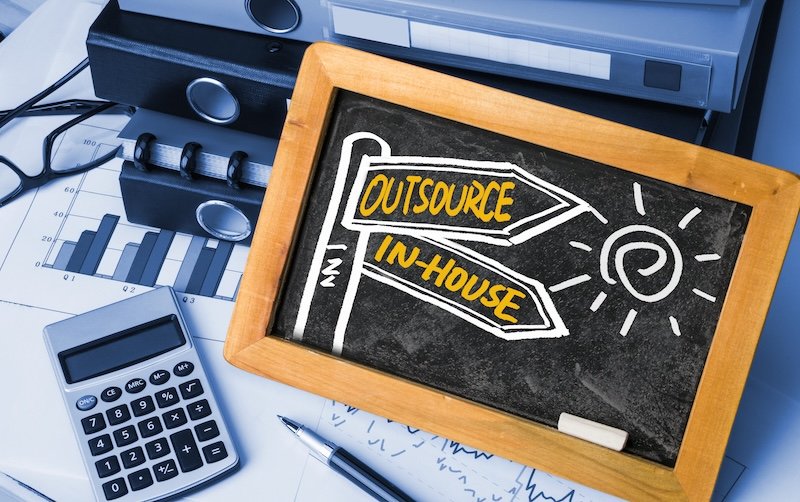 outsource or in-house signpost concept hand drawing on blackboard